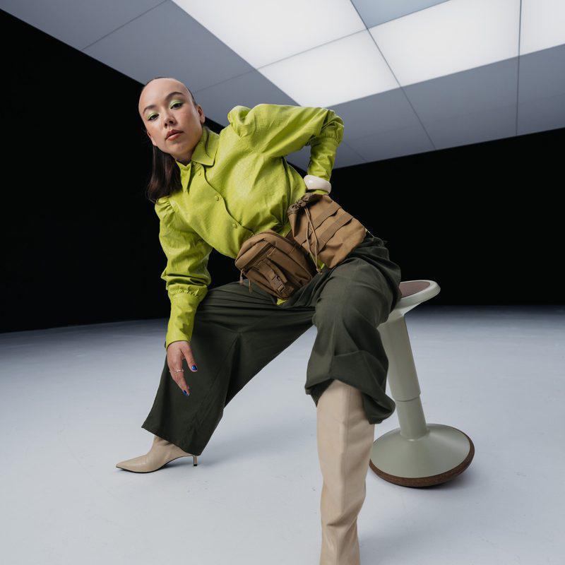 Model in een limegroene blouse op een zadelkruk