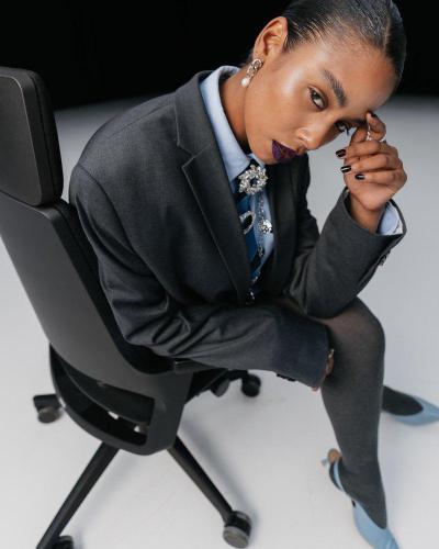Model in een grijs pak op een bureaustoel