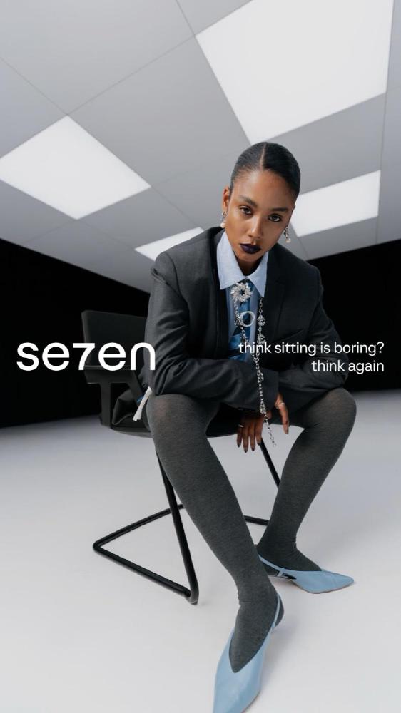 Model in een grijs pak op een Se7en-stoel, advertentie "think sitting is boring? think again"