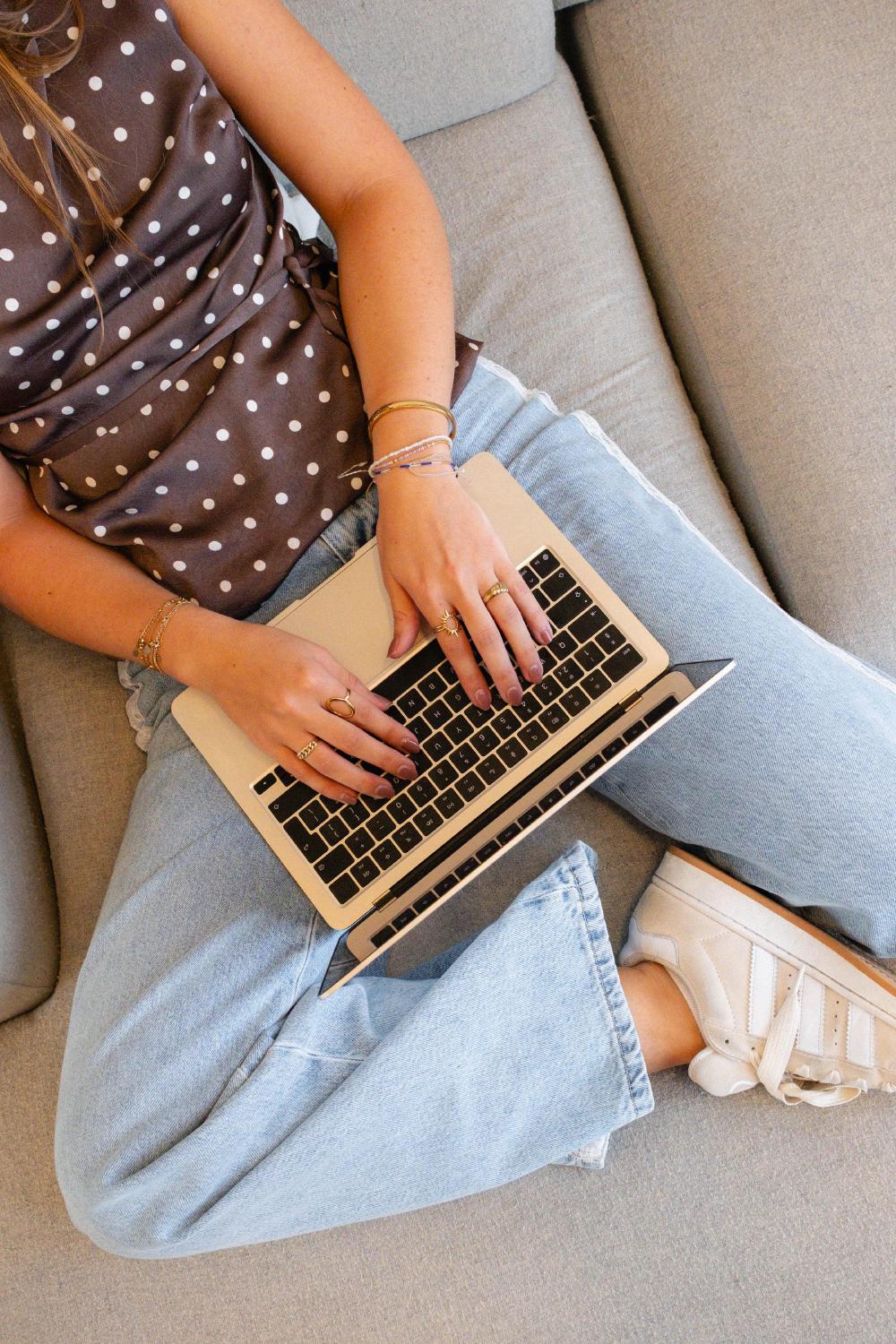 Iemand typt op een laptop op een lichtgrijze bank