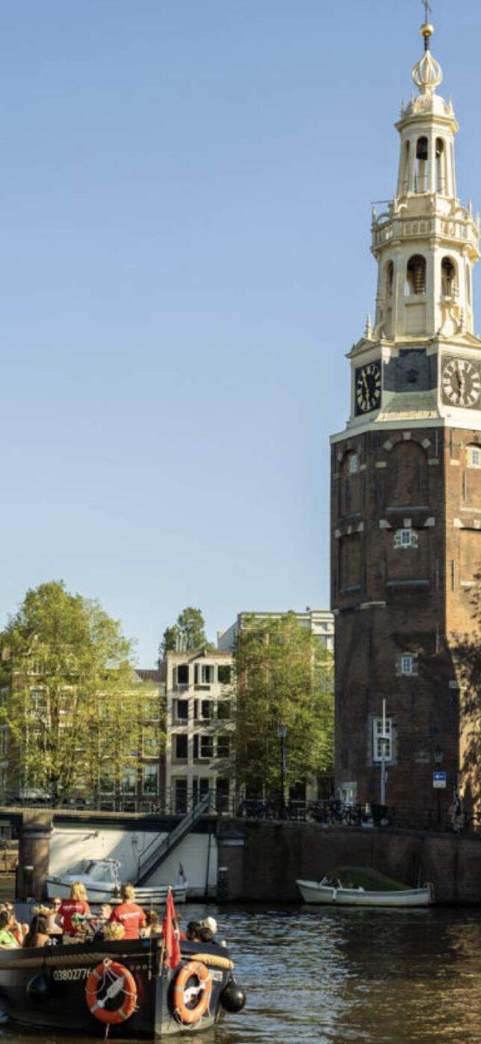 A Mokumboot boat sailing past the Montelbaanstoren tower
