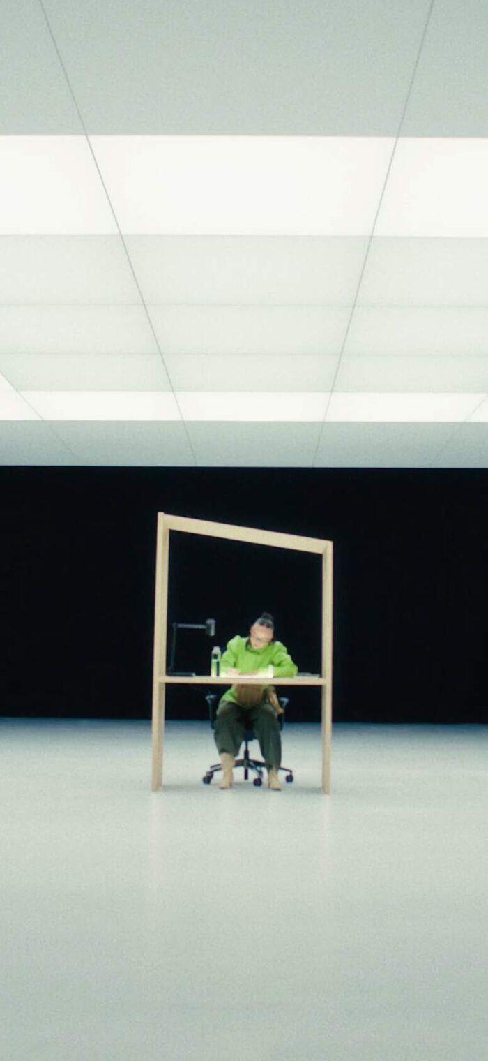 Se7en campaign visual, a model at a desk in an empty white room