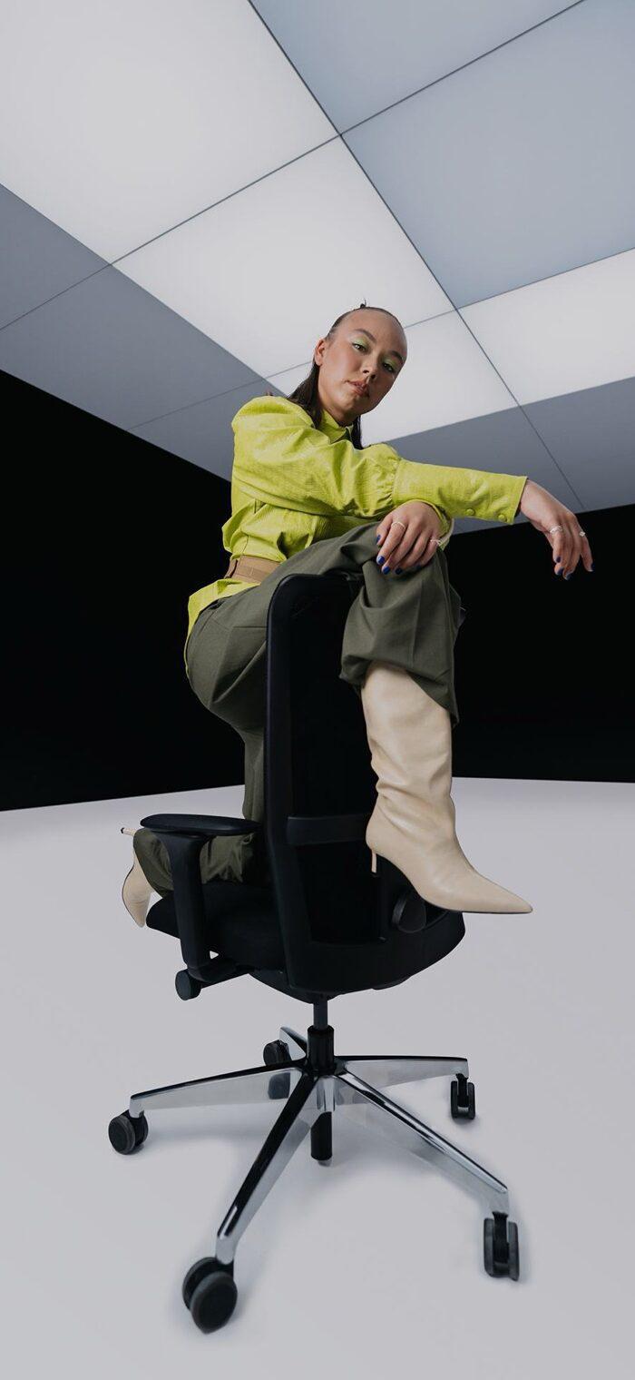 Se7en story with a model in a yellow coat on an office chair